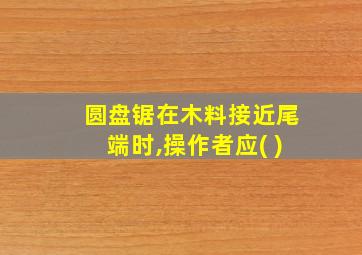 圆盘锯在木料接近尾端时,操作者应( )